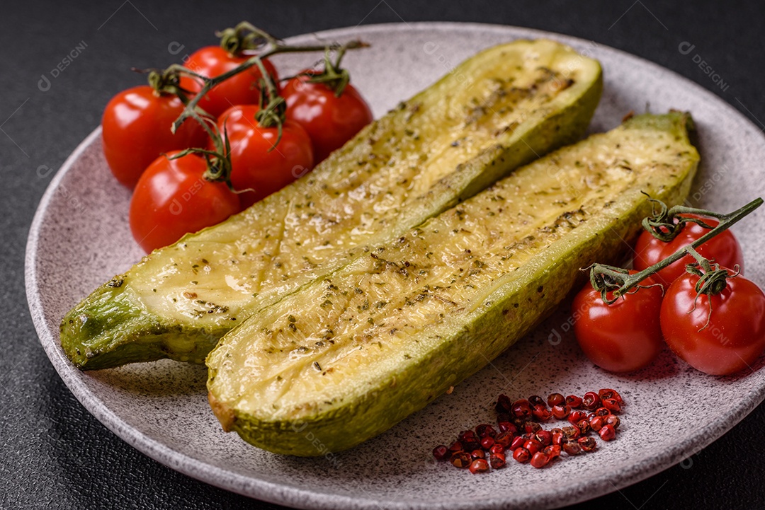 A imagem mostra uma abobrinha italiana assada ou grelhada, servida em um prato com tomate cereja e temperos