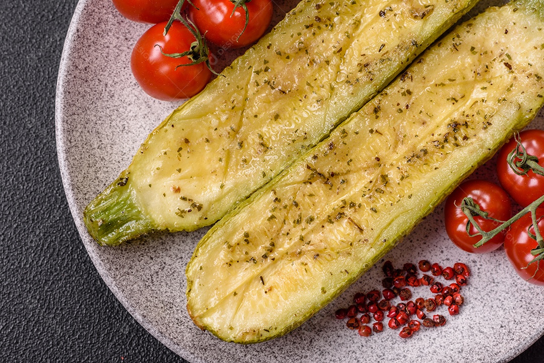 A imagem mostra uma abobrinha italiana assada ou grelhada, servida em um prato com tomate cereja e temperos