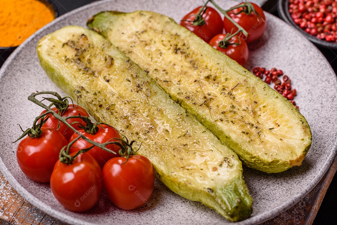 A imagem mostra uma abobrinha italiana assada ou grelhada, servida em um prato com tomate cereja e temperos