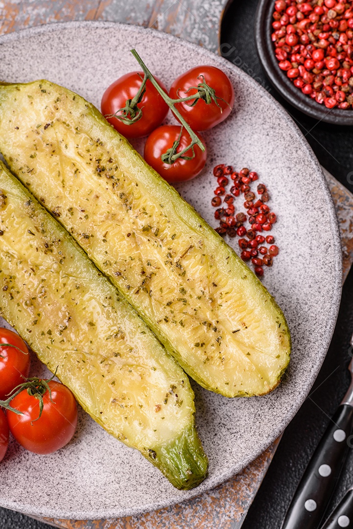 A imagem mostra uma abobrinha italiana assada ou grelhada, servida em um prato com tomate cereja e temperos