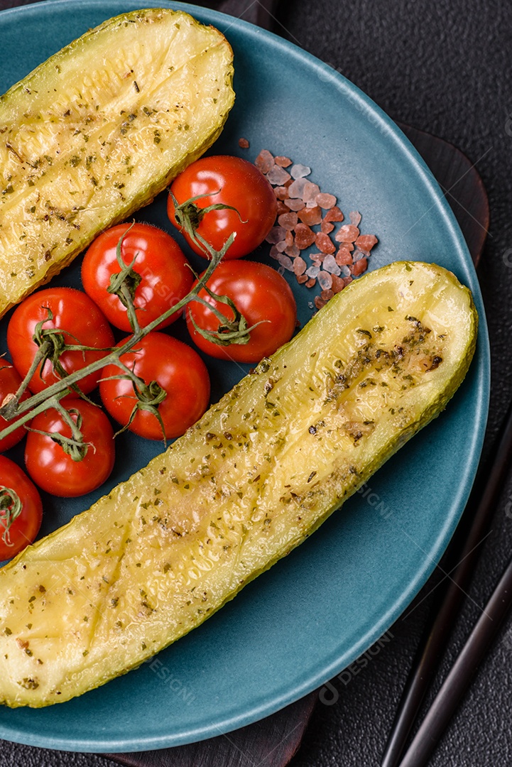 A imagem mostra uma abobrinha italiana assada ou grelhada, servida em um prato com tomate cereja e temperos