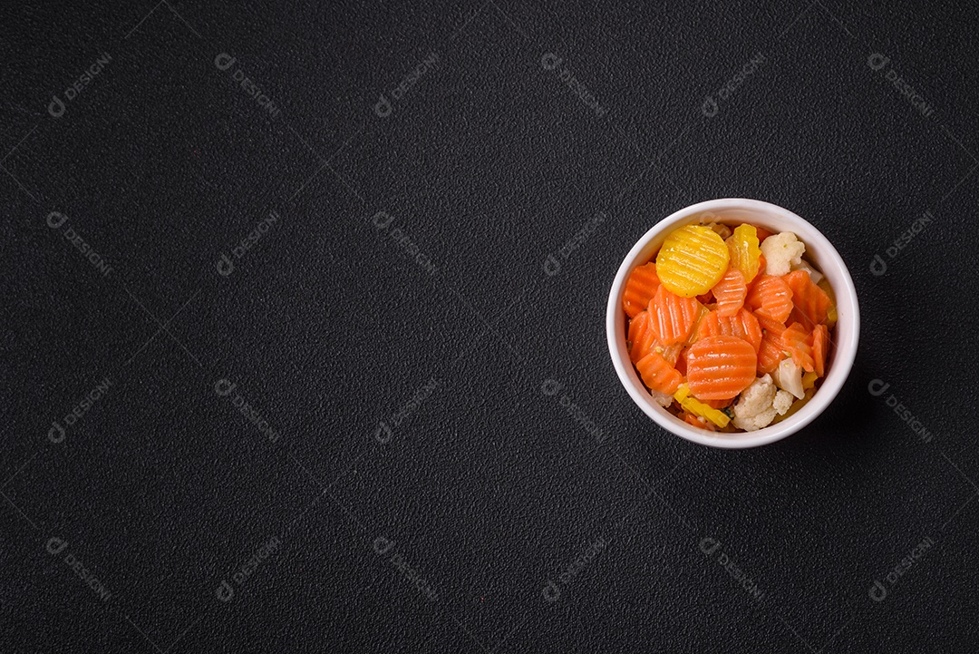 A imagem mostra uma mistura de vegetais congelados, como rodelas de cenoura e brócolis.