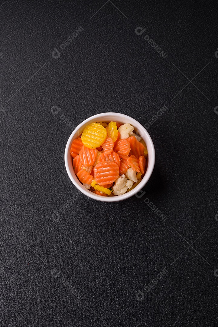 A imagem mostra uma mistura de vegetais congelados, como rodelas de cenoura e brócolis.