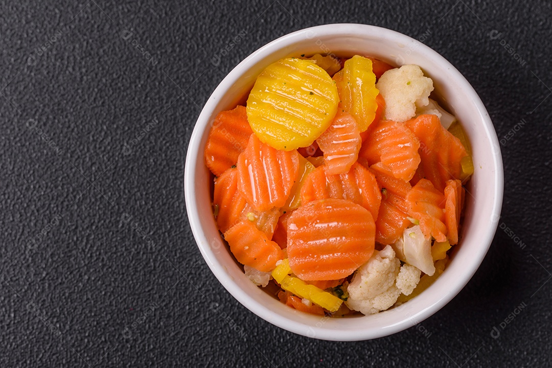 A imagem mostra uma mistura de vegetais congelados, como rodelas de cenoura e brócolis.