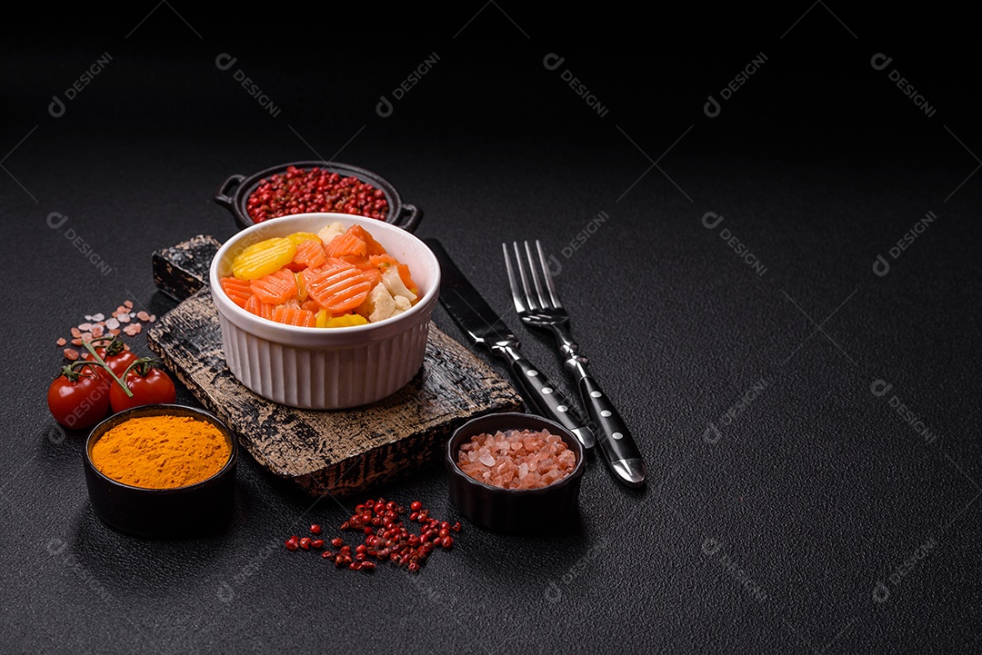 A imagem mostra uma mistura de vegetais congelados, como rodelas de cenoura e brócolis.