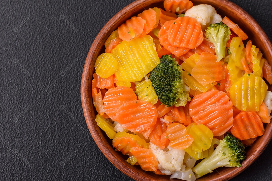 A imagem mostra uma mistura de vegetais congelados, como rodelas de cenoura e brócolis.