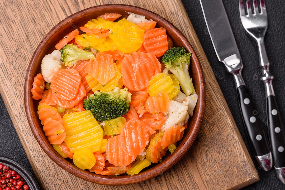 A imagem mostra uma mistura de vegetais congelados, como rodelas de cenoura e brócolis.