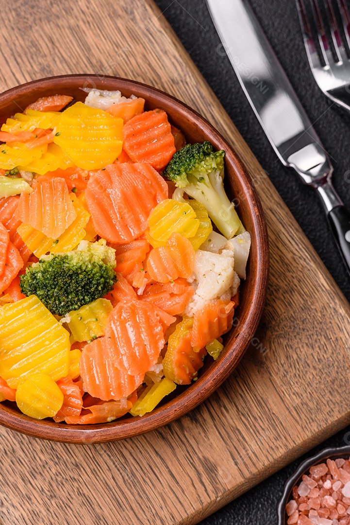 A imagem mostra uma mistura de vegetais congelados, como rodelas de cenoura e brócolis.