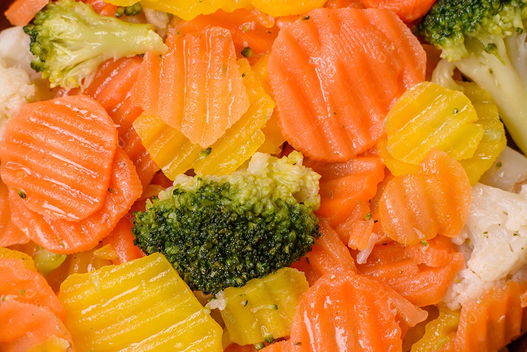 A imagem mostra uma mistura de vegetais congelados, como rodelas de cenoura e brócolis.