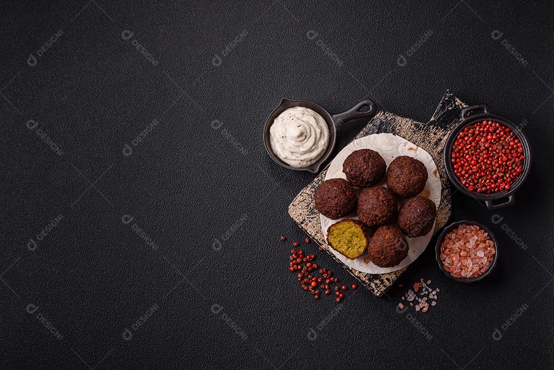 A imagem mostra bolinhos de faláfel servidos em um pão achatado.