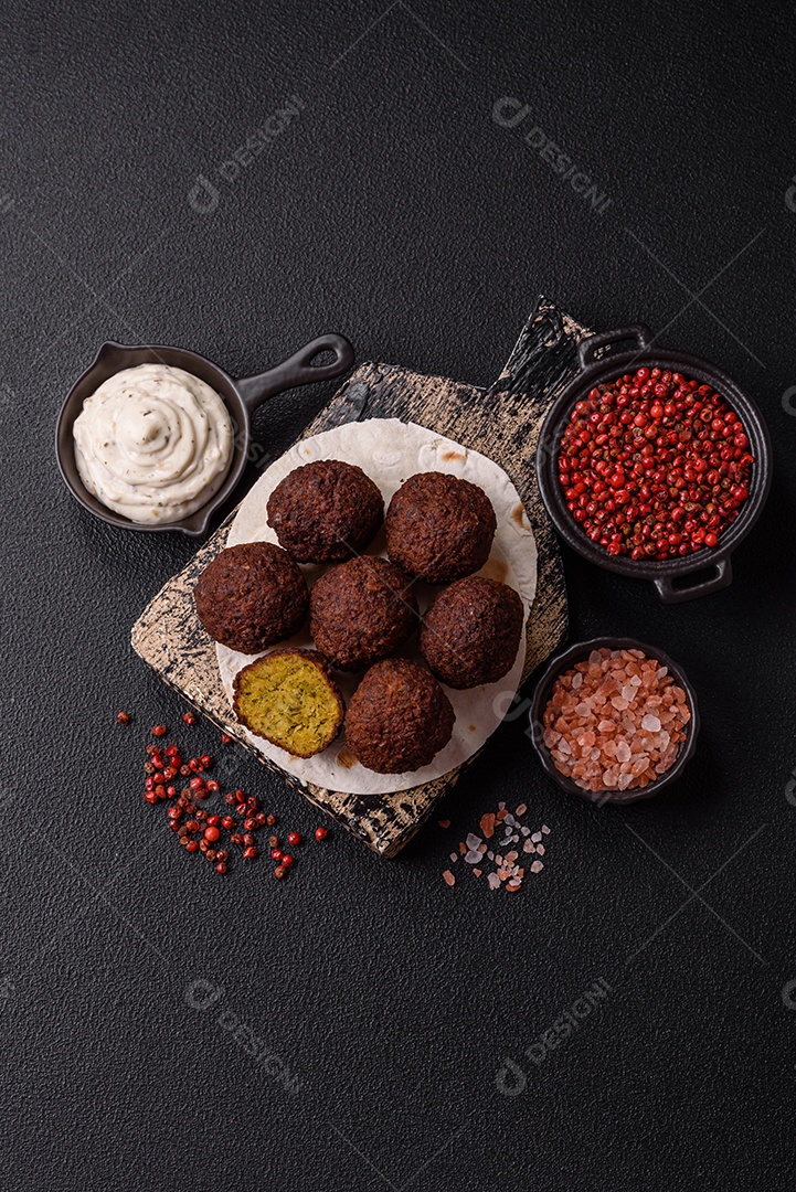 A imagem mostra bolinhos de faláfel servidos em um pão achatado.