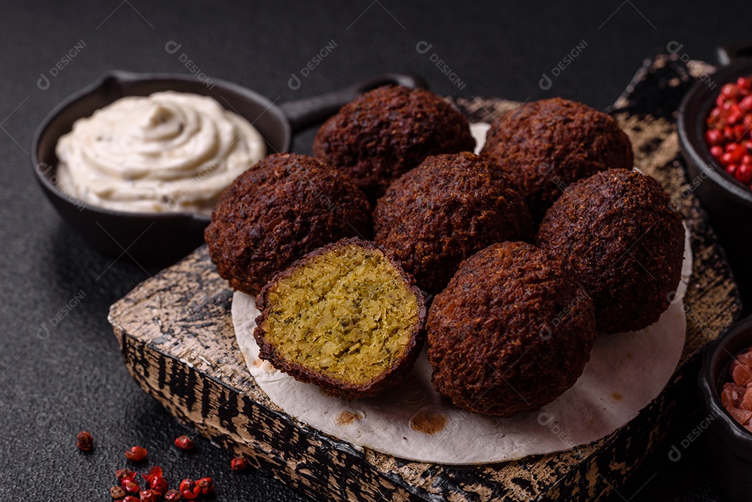 A imagem mostra bolinhos de faláfel servidos em um pão achatado.