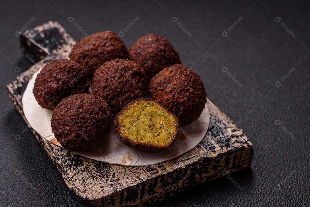 A imagem mostra bolinhos de faláfel servidos em um pão achatado.