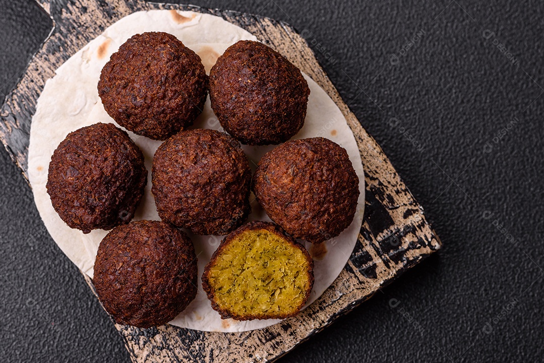 A imagem mostra bolinhos de faláfel servidos em um pão achatado.