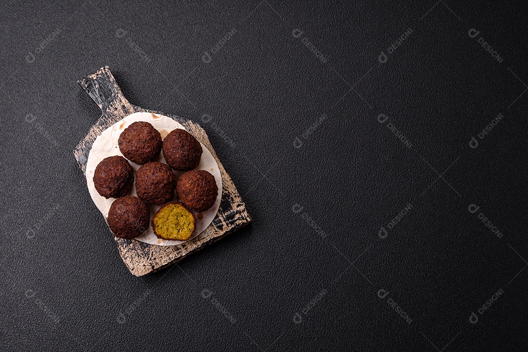 A imagem mostra bolinhos de faláfel servidos em um pão achatado.