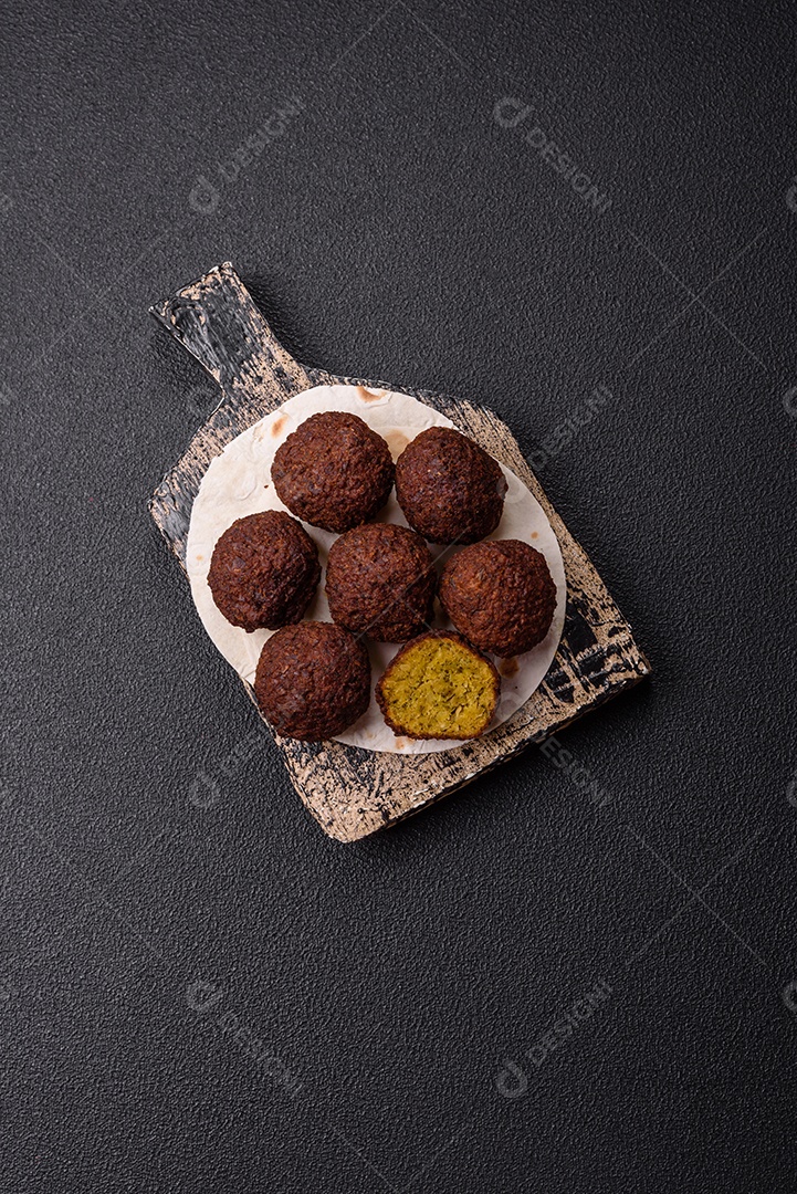 A imagem mostra bolinhos de faláfel servidos em um pão achatado.