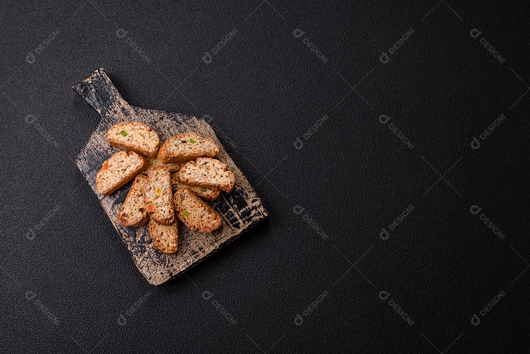 A imagem mostra uma seleção de biscoitos natalinos, incluindo biscoitos de pão de gengibre decorados e fatias de cantuccini com nozes e frutas cristalizadas.