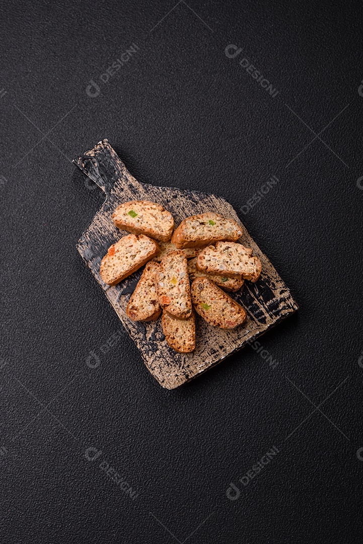 A imagem mostra uma seleção de biscoitos natalinos, incluindo biscoitos de pão de gengibre decorados e fatias de cantuccini com nozes e frutas cristalizadas.