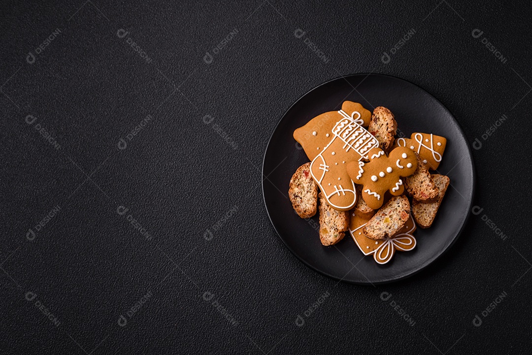 A imagem mostra uma seleção de biscoitos natalinos, incluindo biscoitos de pão de gengibre decorados e fatias de cantuccini com nozes e frutas cristalizadas.