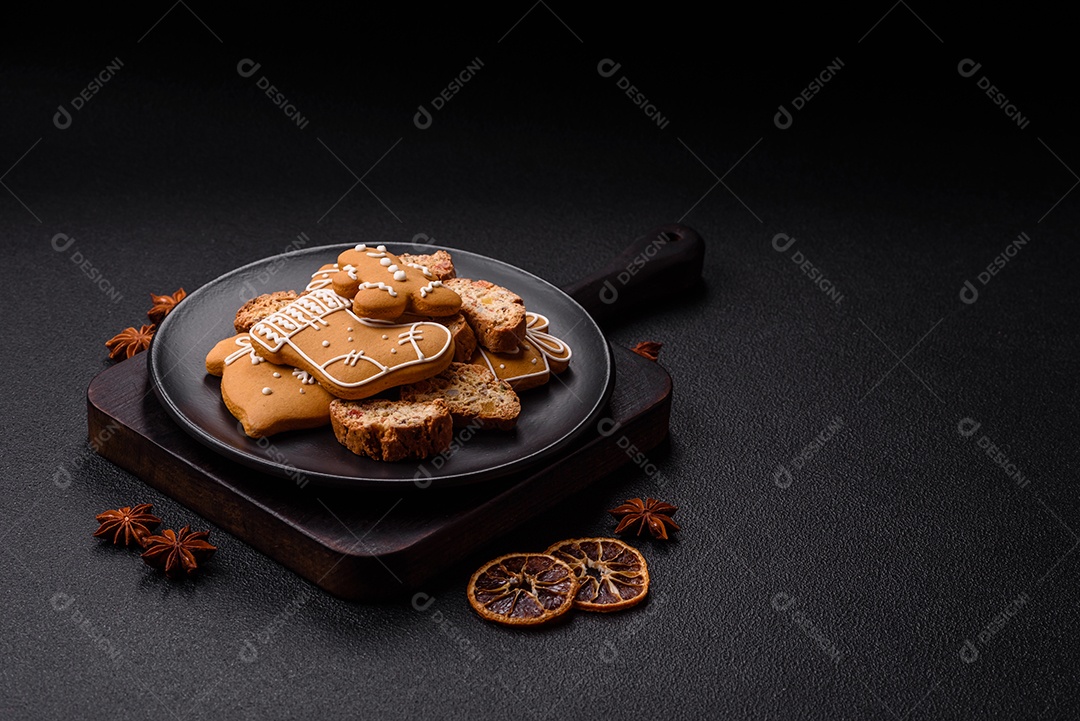 A imagem mostra uma seleção de biscoitos natalinos, incluindo biscoitos de pão de gengibre decorados e fatias de cantuccini com nozes e frutas cristalizadas.