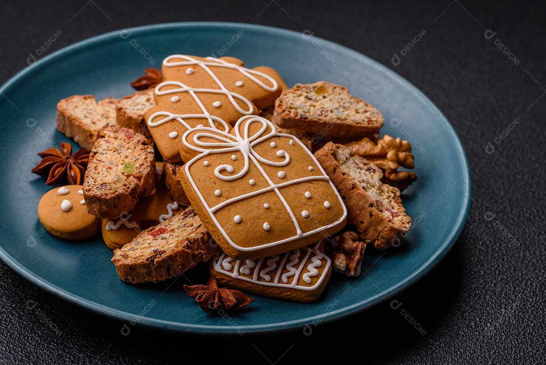 A imagem mostra uma seleção de biscoitos natalinos, incluindo biscoitos de pão de gengibre decorados e fatias de cantuccini com nozes e frutas cristalizadas.