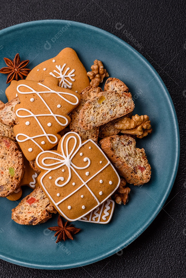 A imagem mostra uma seleção de biscoitos natalinos, incluindo biscoitos de pão de gengibre decorados e fatias de cantuccini com nozes e frutas cristalizadas.