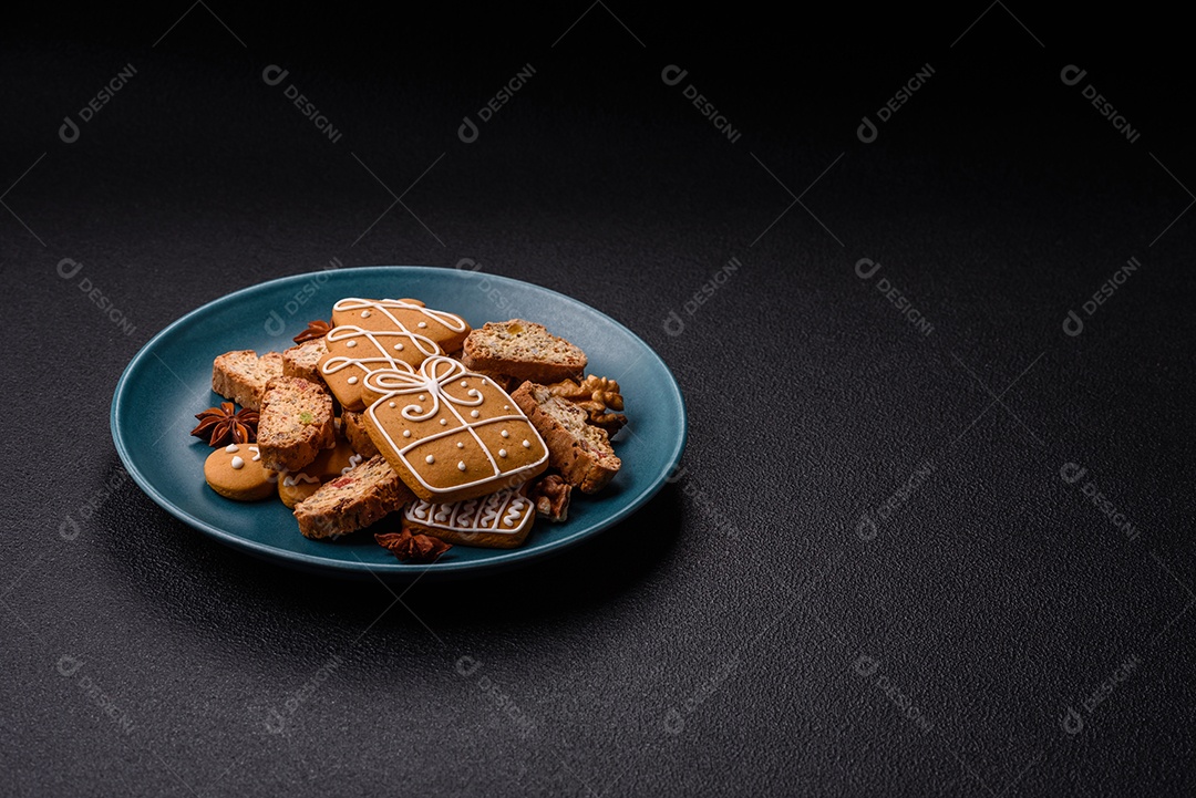 A imagem mostra uma seleção de biscoitos natalinos, incluindo biscoitos de pão de gengibre decorados e fatias de cantuccini com nozes e frutas cristalizadas.