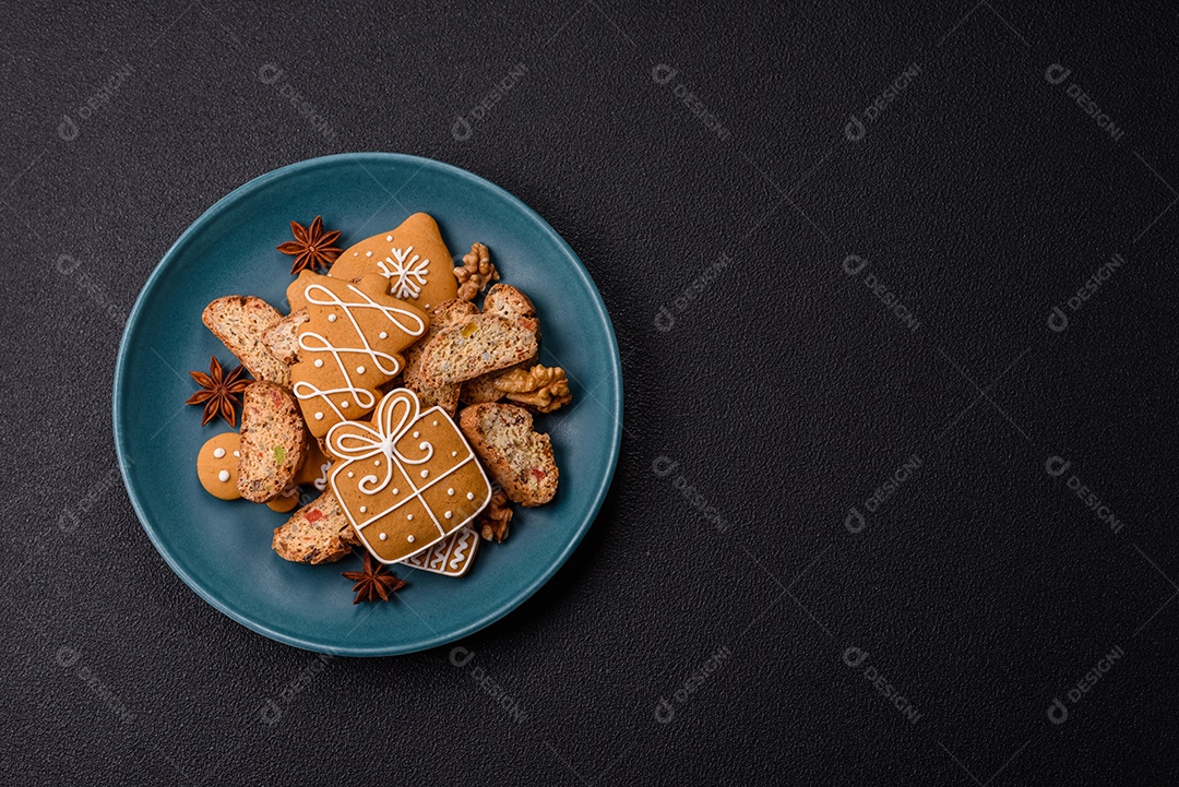 A imagem mostra uma seleção de biscoitos natalinos, incluindo biscoitos de pão de gengibre decorados e fatias de cantuccini com nozes e frutas cristalizadas.