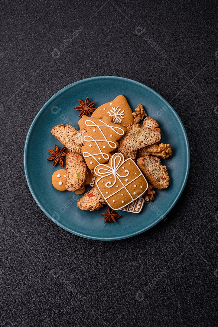 A imagem mostra uma seleção de biscoitos natalinos, incluindo biscoitos de pão de gengibre decorados e fatias de cantuccini com nozes e frutas cristalizadas.