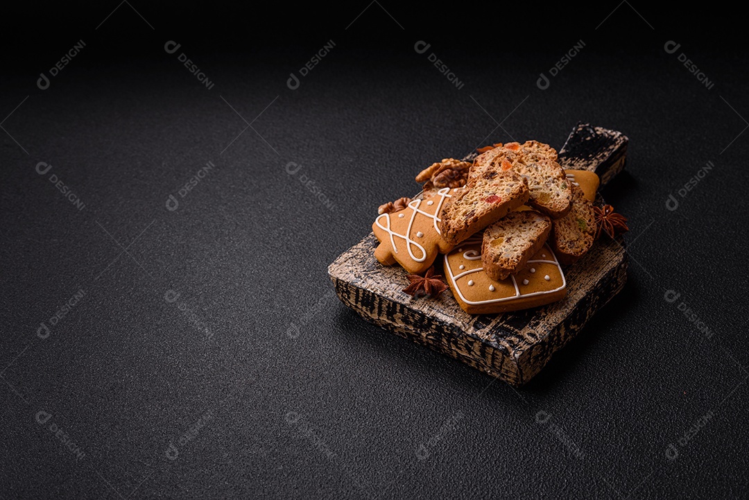 A imagem mostra uma seleção de biscoitos natalinos, incluindo biscoitos de pão de gengibre decorados e fatias de cantuccini com nozes e frutas cristalizadas.