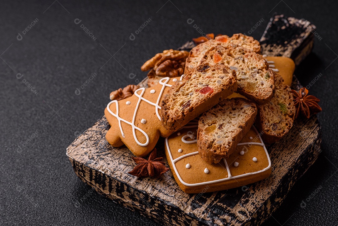 A imagem mostra uma seleção de biscoitos natalinos, incluindo biscoitos de pão de gengibre decorados e fatias de cantuccini com nozes e frutas cristalizadas.