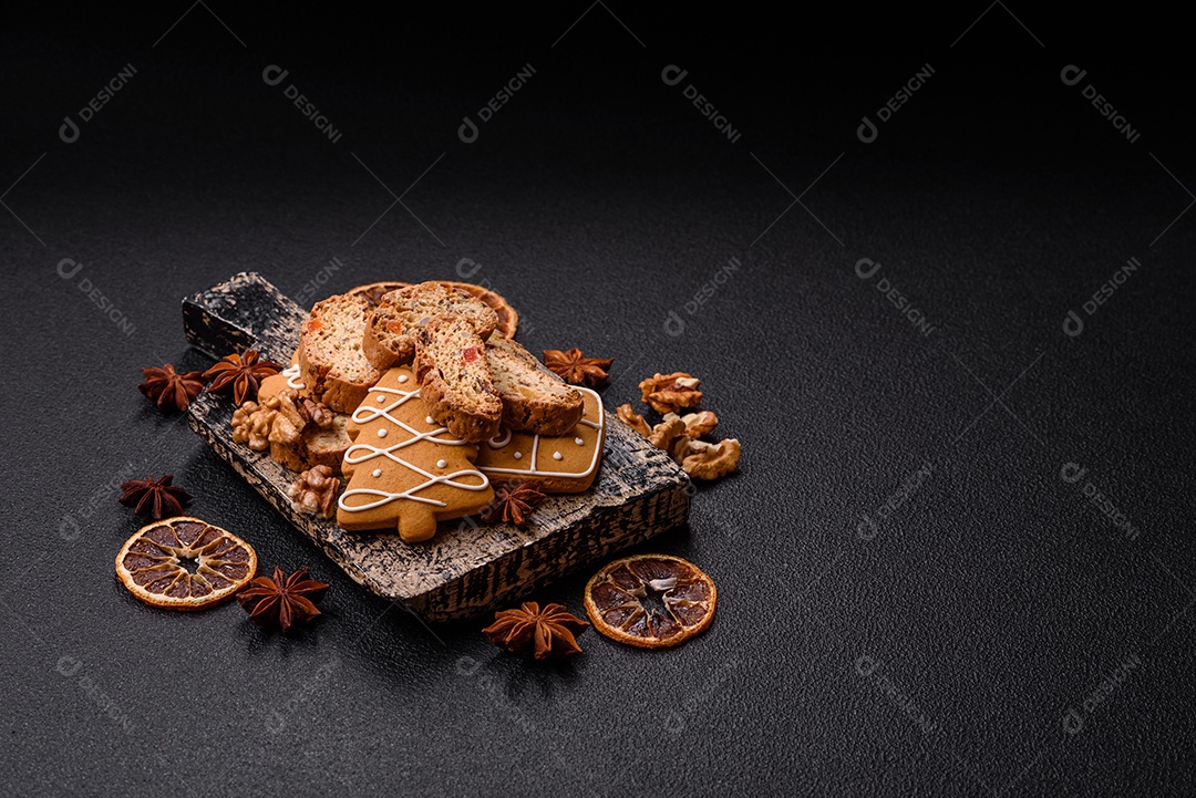 A imagem mostra uma seleção de biscoitos natalinos, incluindo biscoitos de pão de gengibre decorados e fatias de cantuccini com nozes e frutas cristalizadas.