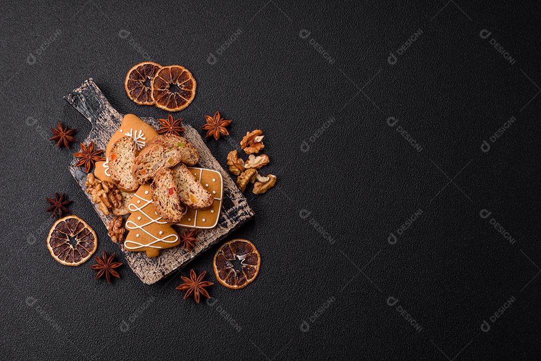 A imagem mostra uma seleção de biscoitos natalinos, incluindo biscoitos de pão de gengibre decorados e fatias de cantuccini com nozes e frutas cristalizadas.