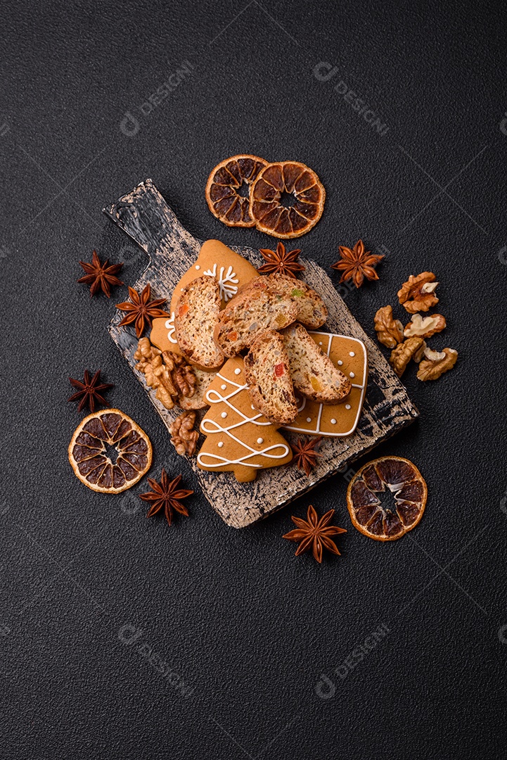 A imagem mostra uma seleção de biscoitos natalinos, incluindo biscoitos de pão de gengibre decorados e fatias de cantuccini com nozes e frutas cristalizadas.