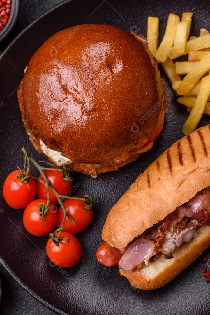 A imagem mostra um prato com um cachorro-quente e um hambúrguer, ambos servidos com batatas fritas e tomates cereja