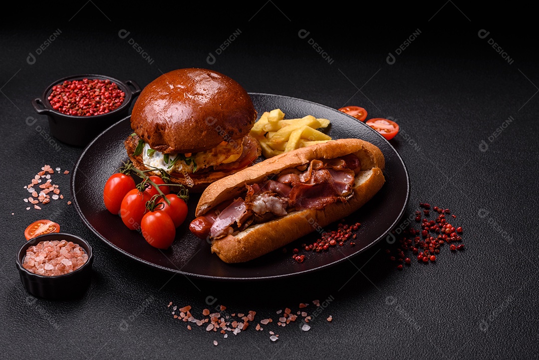 A imagem mostra um prato com um cachorro-quente e um hambúrguer, ambos servidos com batatas fritas e tomates cereja