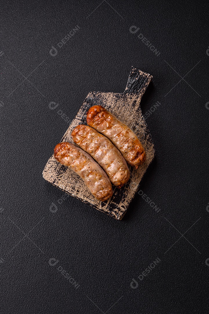 Três linguiças ou salsichas grelhadas são apresentadas em um prato, com temperos e tomates-cereja cortados.