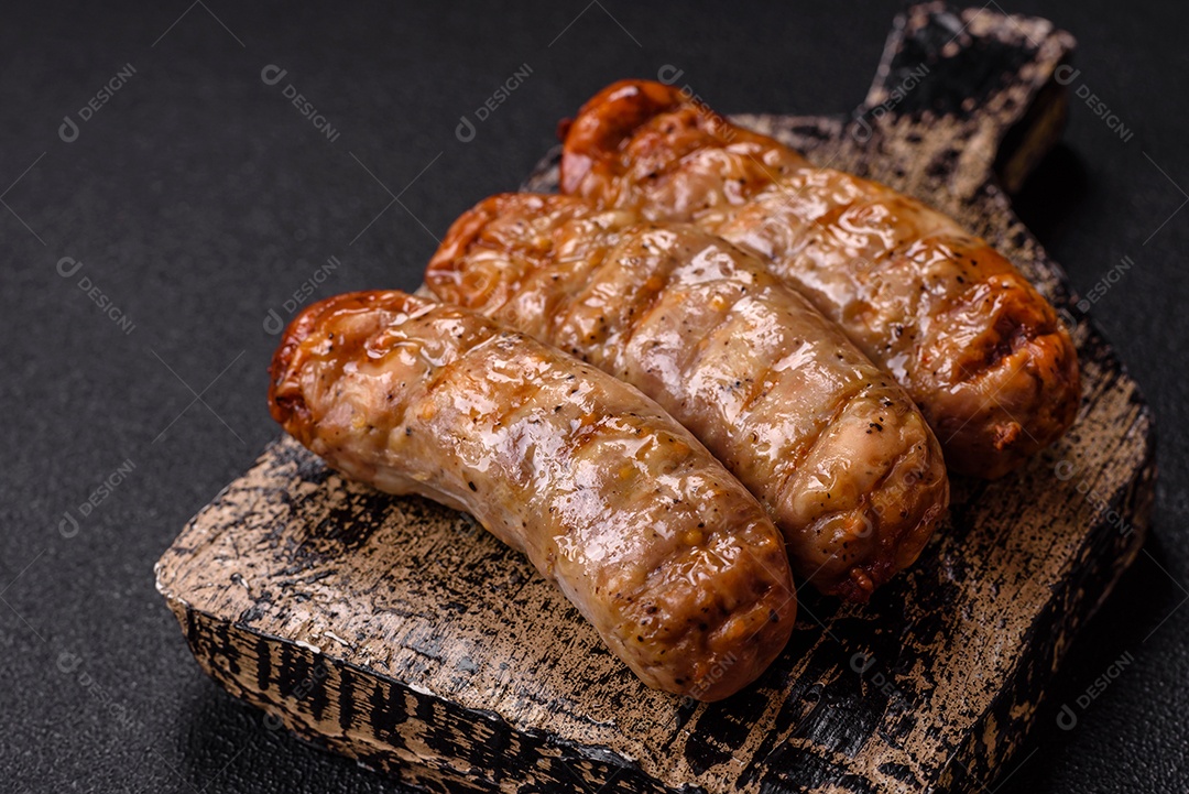 Três linguiças ou salsichas grelhadas são apresentadas em um prato, com temperos e tomates-cereja cortados.