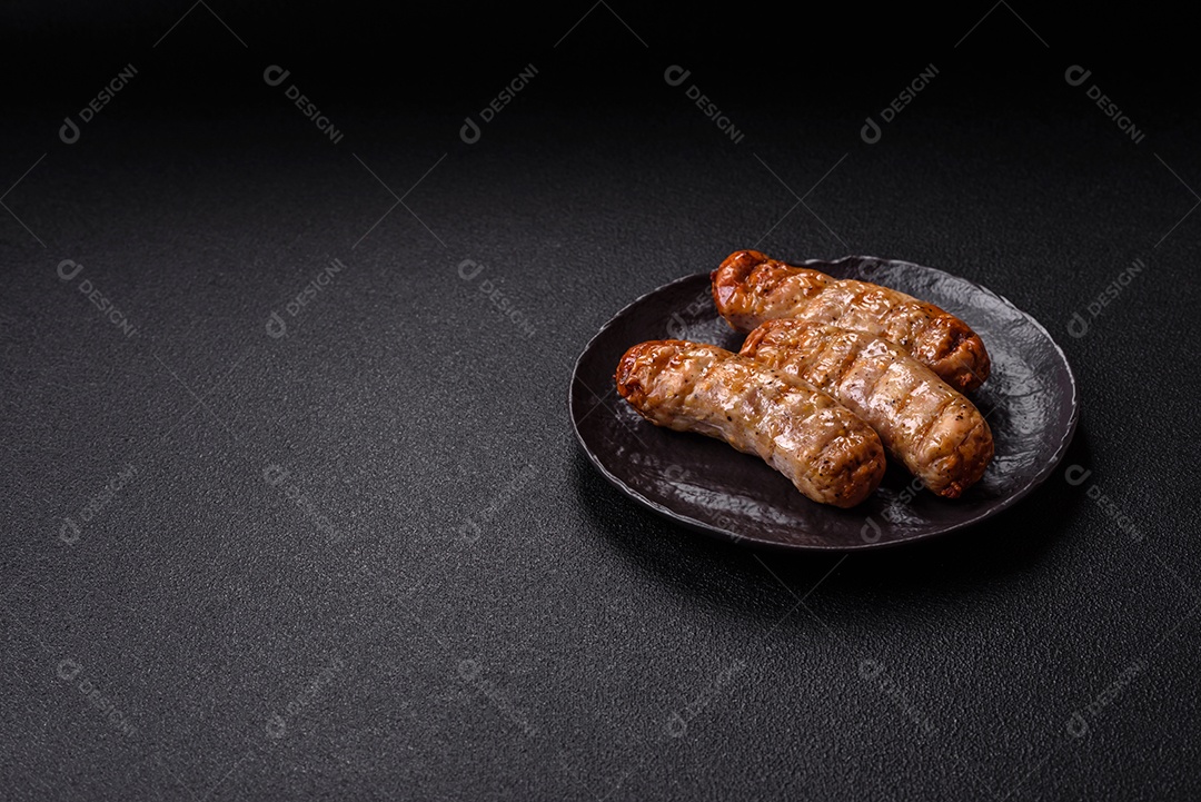 Três linguiças ou salsichas grelhadas são apresentadas em um prato, com temperos e tomates-cereja cortados.