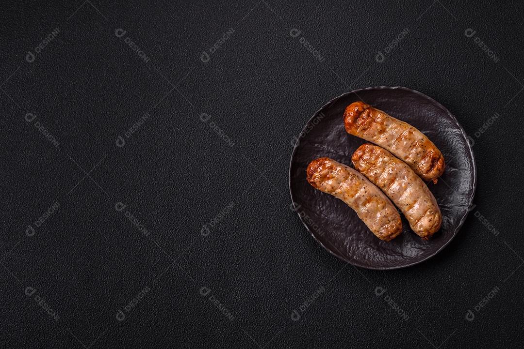 Três linguiças ou salsichas grelhadas são apresentadas em um prato, com temperos e tomates-cereja cortados.