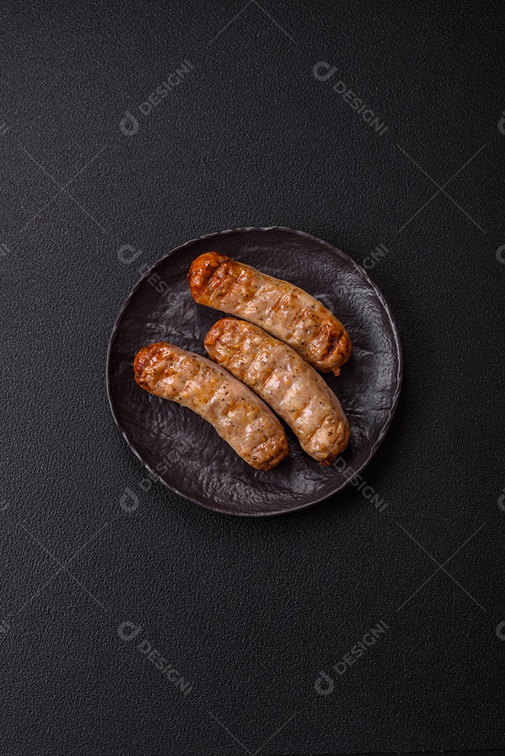 Três linguiças ou salsichas grelhadas são apresentadas em um prato, com temperos e tomates-cereja cortados.