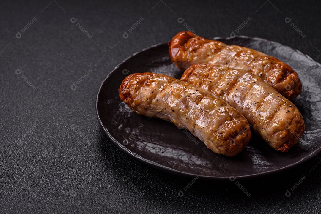 Três linguiças ou salsichas grelhadas são apresentadas em um prato, com temperos e tomates-cereja cortados.