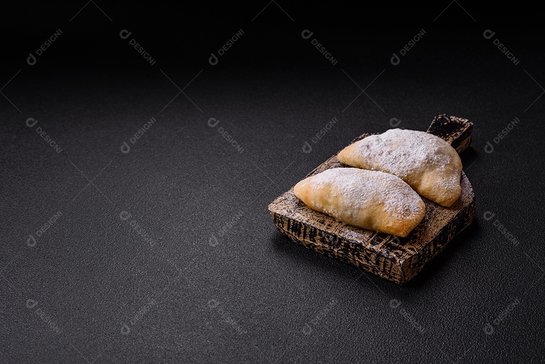 A imagem mostra biscoitos ou pastéis polvilhados com açúcar de confeiteiro, que podem ser semelhantes ao pastel de carne com açúcar
