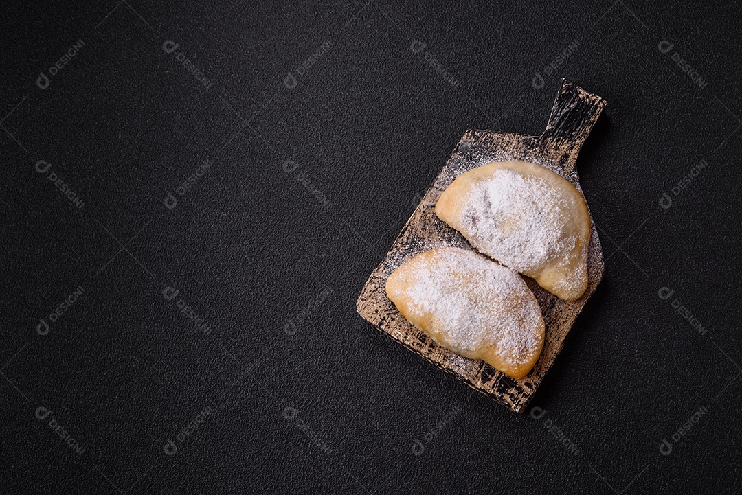 A imagem mostra biscoitos ou pastéis polvilhados com açúcar de confeiteiro, que podem ser semelhantes ao pastel de carne com açúcar