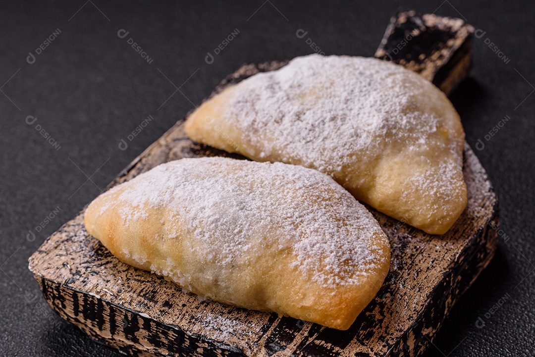 A imagem mostra biscoitos ou pastéis polvilhados com açúcar de confeiteiro, que podem ser semelhantes ao pastel de carne com açúcar
