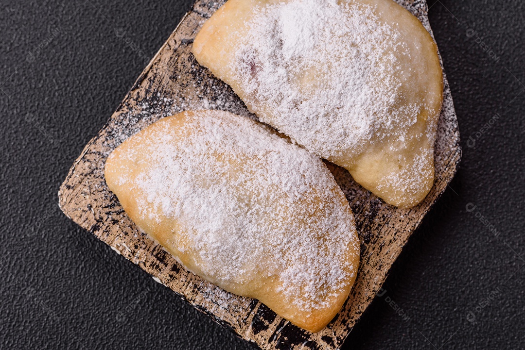 A imagem mostra biscoitos ou pastéis polvilhados com açúcar de confeiteiro, que podem ser semelhantes ao pastel de carne com açúcar