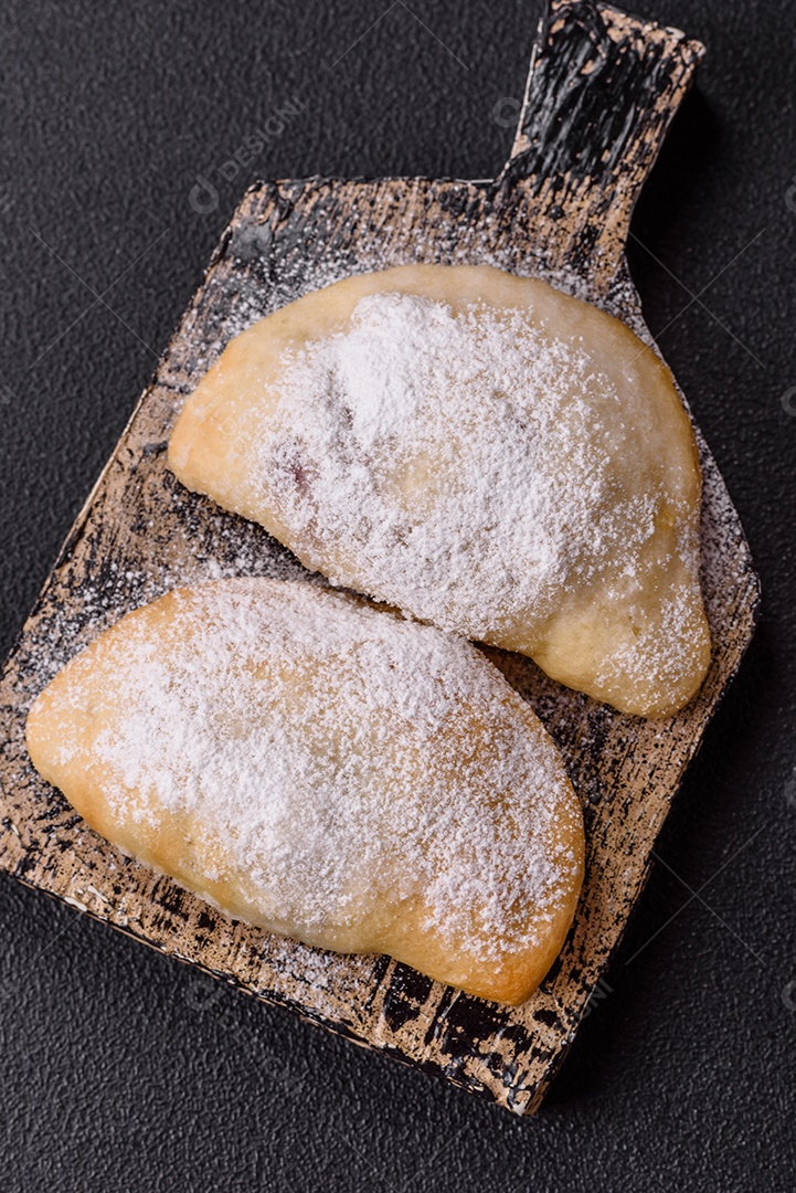 A imagem mostra biscoitos ou pastéis polvilhados com açúcar de confeiteiro, que podem ser semelhantes ao pastel de carne com açúcar