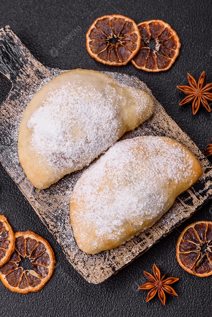 A imagem mostra biscoitos ou pastéis polvilhados com açúcar de confeiteiro, que podem ser semelhantes ao pastel de carne com açúcar