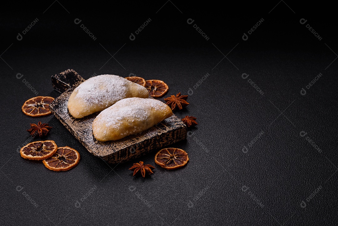 A imagem mostra biscoitos ou pastéis polvilhados com açúcar de confeiteiro, que podem ser semelhantes ao pastel de carne com açúcar