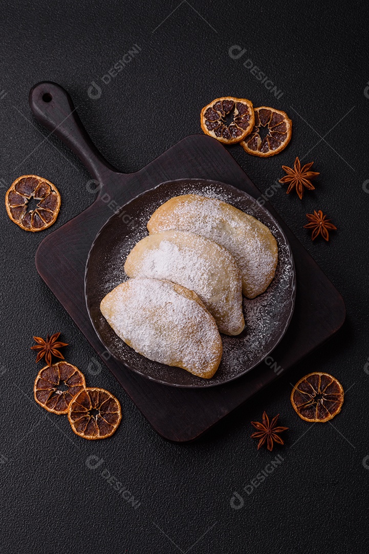 A imagem mostra biscoitos ou pastéis polvilhados com açúcar de confeiteiro, que podem ser semelhantes ao pastel de carne com açúcar